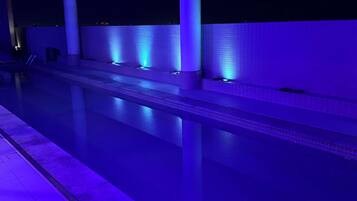 A swimming pool with a tiled edge and a series of lights along the side.