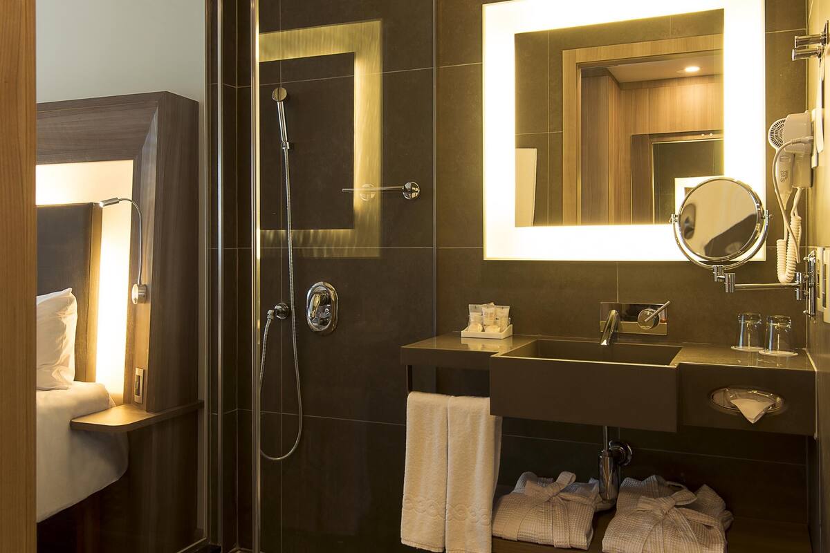 A modern bathroom with a glass-enclosed shower, a vanity with a mirror, and a towel rack.
