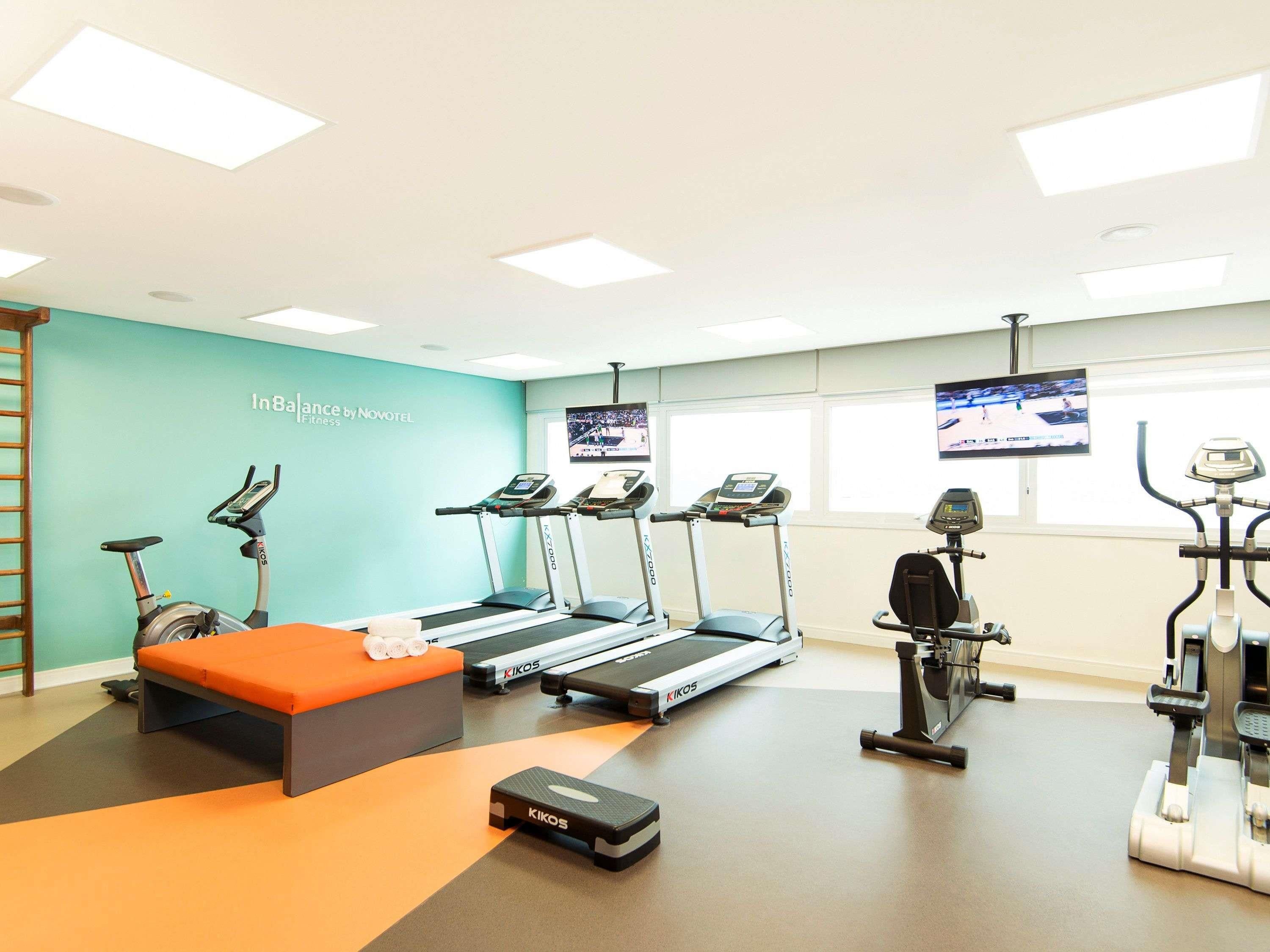 Een fitnessruimte met loopbanden, een hometrainer en een roeimachine.