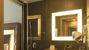 A modern bathroom with a glass-enclosed shower, a large mirror, and a vanity with towels and toiletries. - Novotel Santos Gonzaga (Santos)