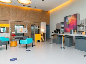A modern lobby with seating areas, a reception desk, and a colorful abstract painting on the wall. - Novotel Santos Gonzaga (Santos)