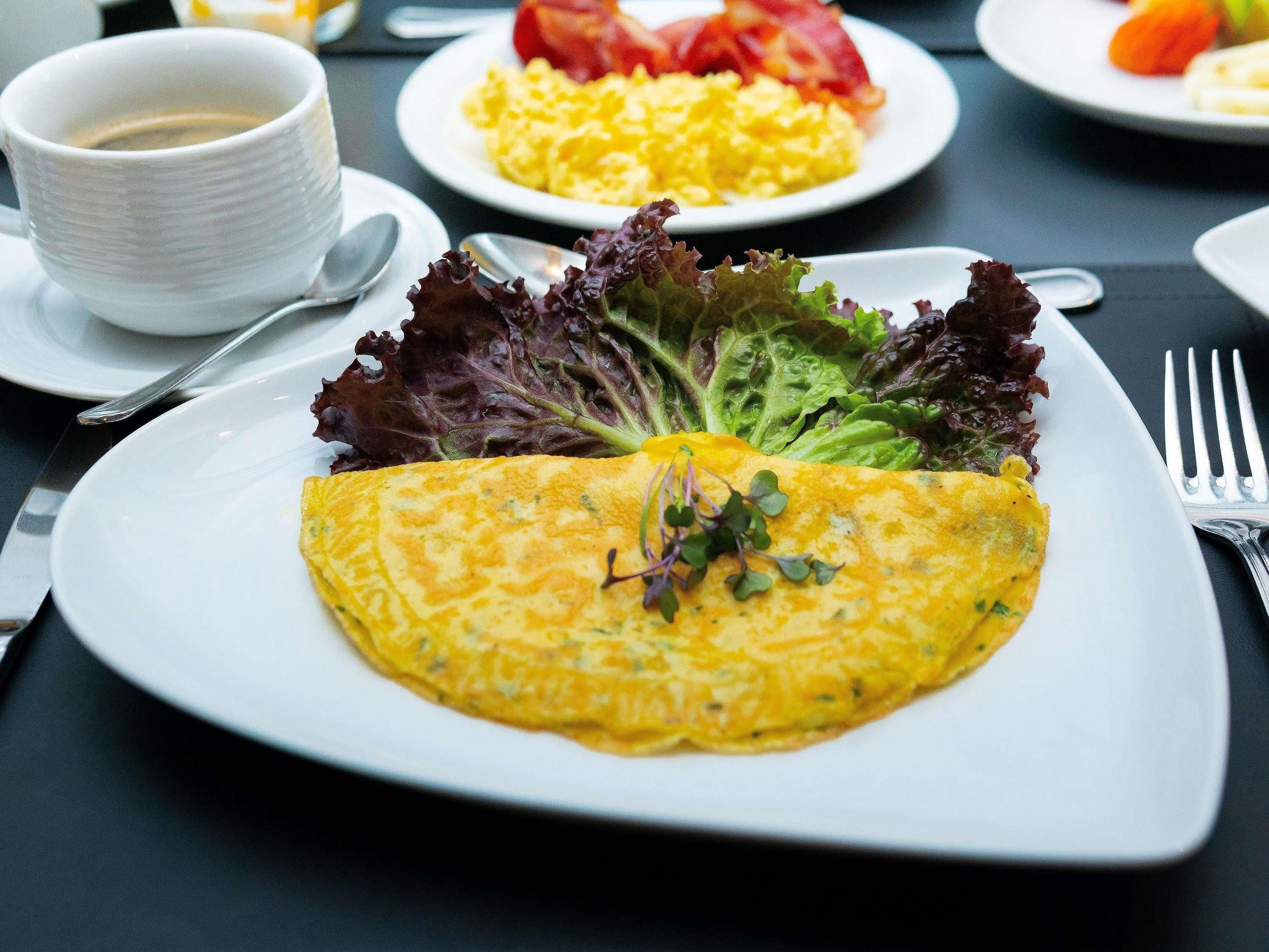 A plate with an omelette, a cup of coffee, and a salad on a table.