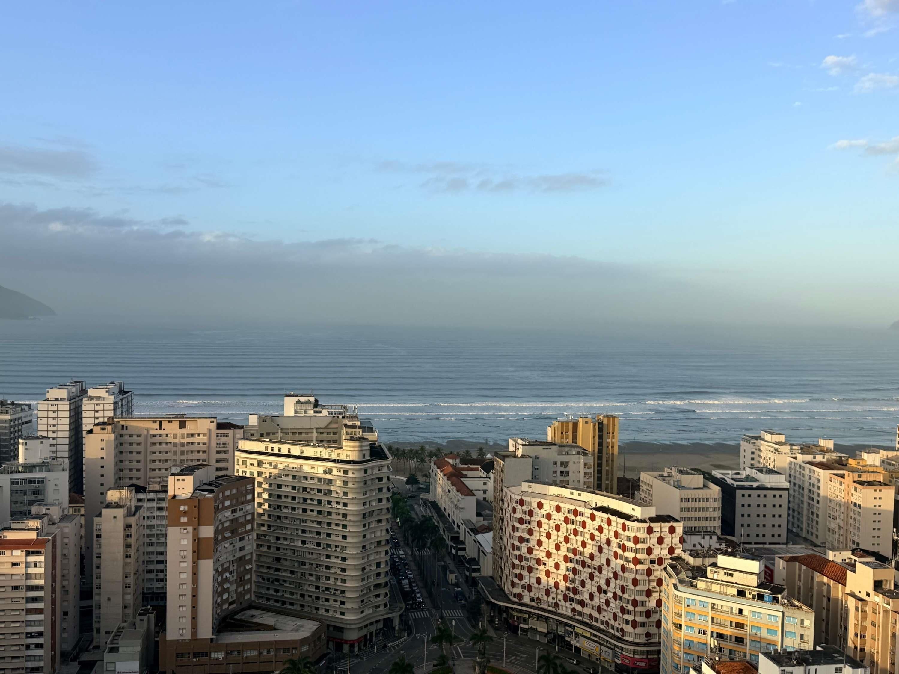 A coastal cityscape with high-rise buildings, a clear sky, and a view of the ocean.