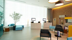A modern lobby with seating areas, reception desks, and a large window providing natural light. - Novotel Santos Gonzaga (Santos)
