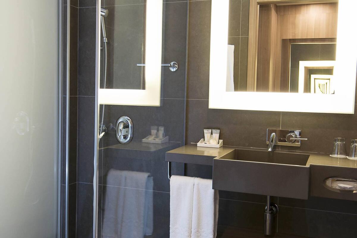 A modern bathroom with a glass-enclosed shower, a vanity with a sink and mirror, and a towel rack.