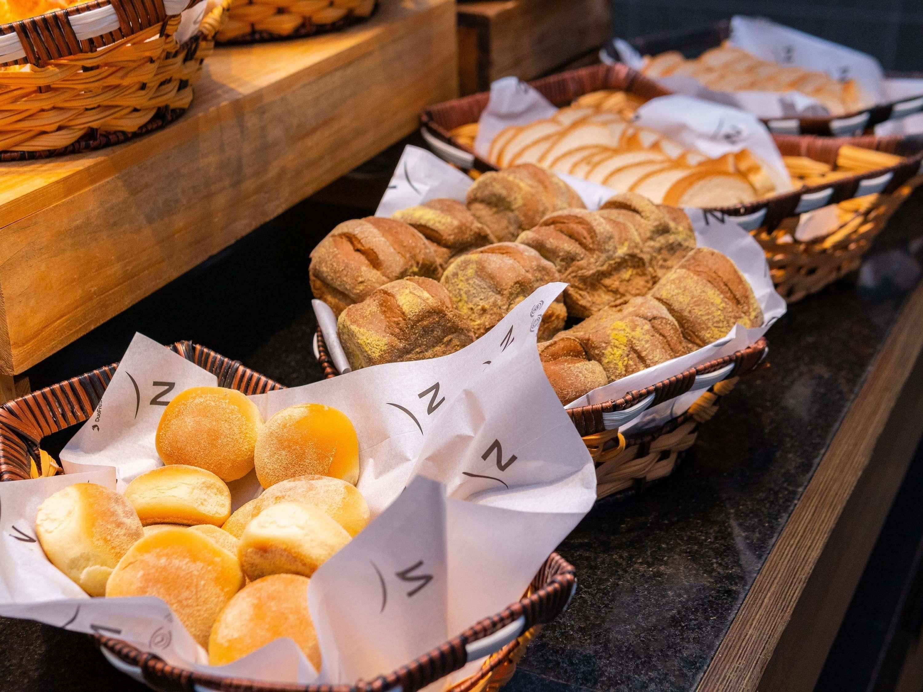 A buffet with various baked goods including bread and rolls.