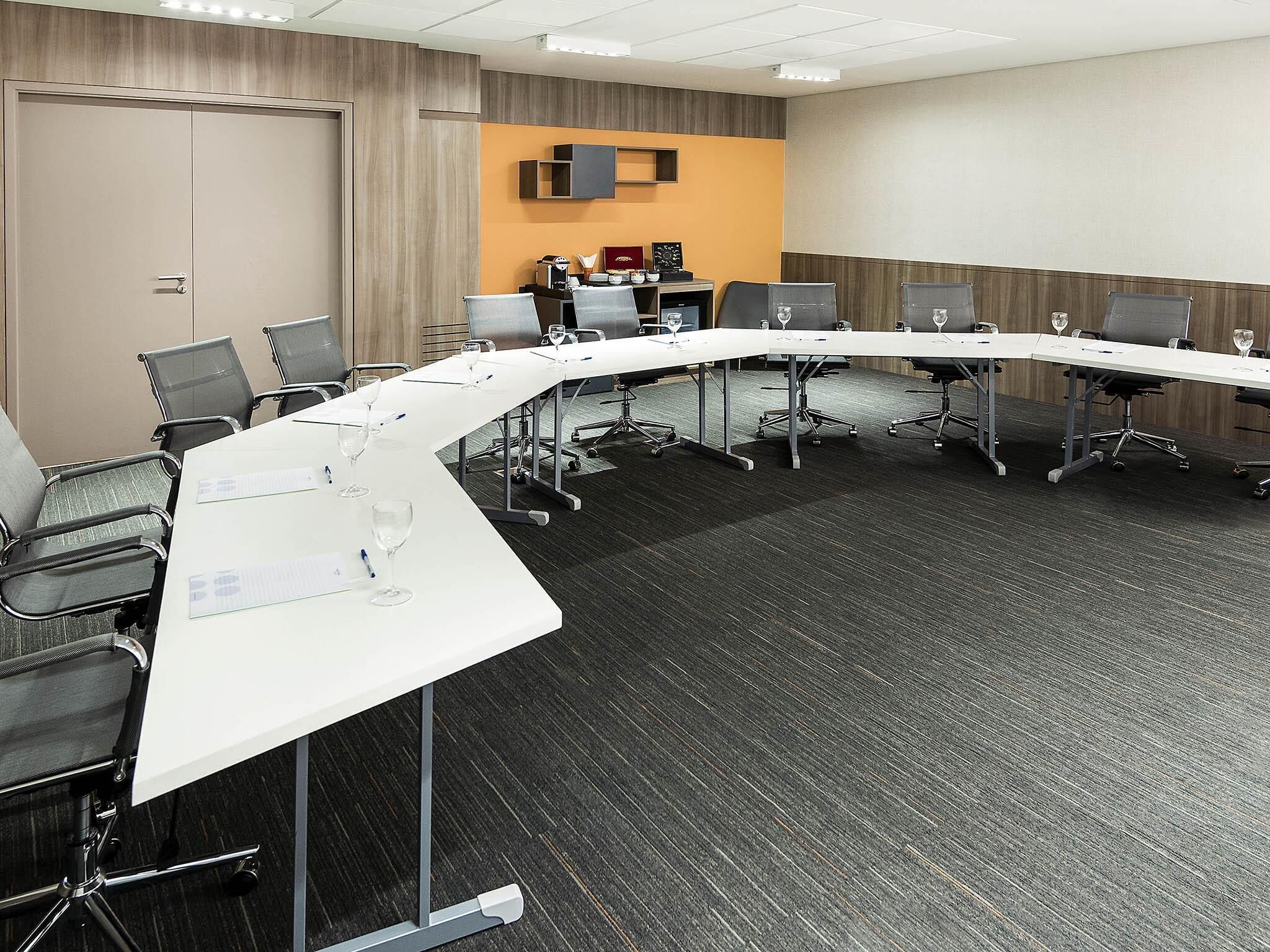 A conference room with a long table, chairs, and a projector screen.