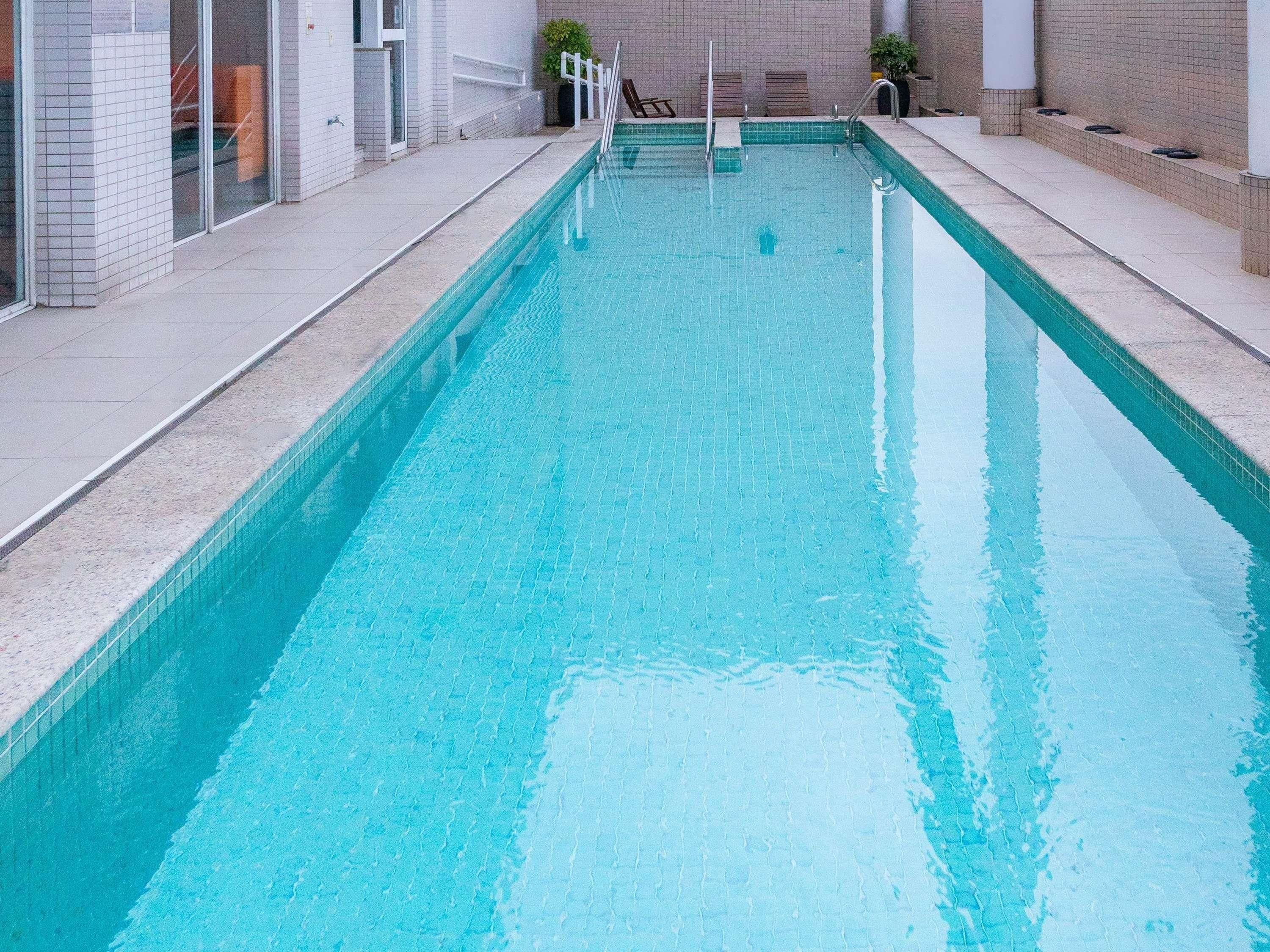 A rectangular indoor swimming pool with clear water, surrounded by tiled walls and a tiled deck.