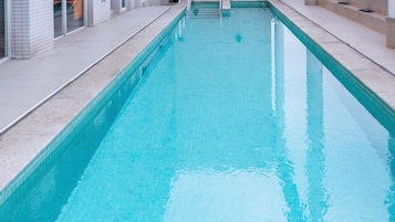 A rectangular indoor swimming pool with clear water, surrounded by tiled walls and a tiled deck.