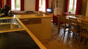 Eine moderne Küche mit Geschirrspüler, Herd und Essbereich mit Holzsesseln und einem Tisch.