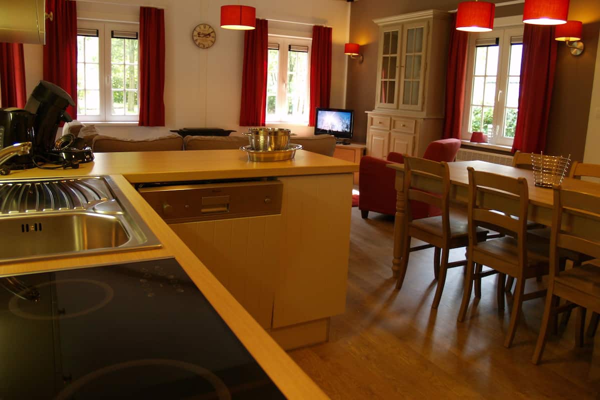 Una cocina moderna con lavavajillas, estufa y comedor con sillas y mesa de madera.
