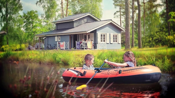 Ein Haus mit Veranda, umgeben von Bäumen und einem Gewässer.