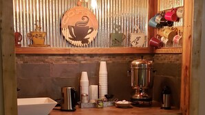 A compact kitchen with a coffee station, including a coffee machine, cups, and a kettle. - Kansas Country Inn (Oakley)