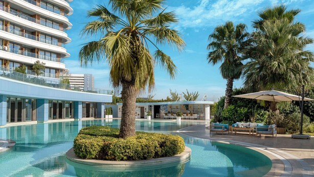 A hotel with a swimming pool, palm trees, and outdoor seating. - Radisson Blu Hotel Istanbul Ottomare (Istanbul)