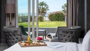 A room with a large window, a dining table with a tray of food, two chairs, and a bed. - Radisson Blu Hotel Istanbul Ottomare (Istanbul)