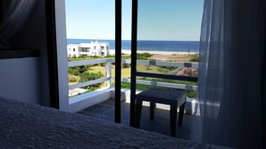 En balkon med udsigt over havet, en hvid bygning og en stol.