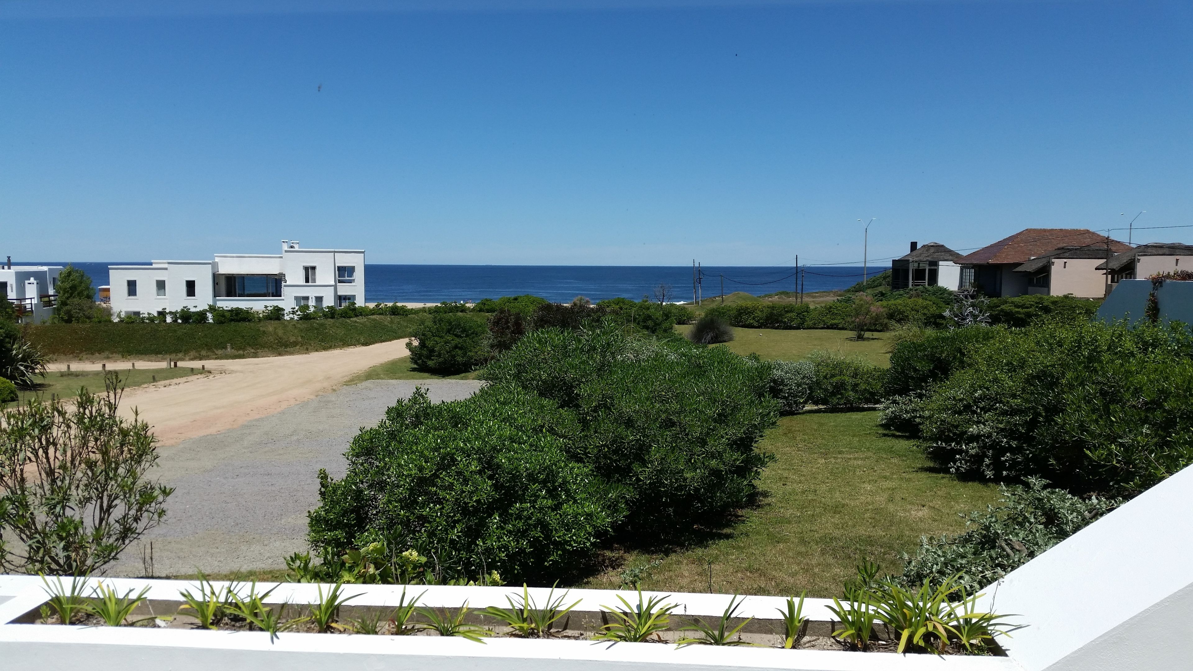 Un quartier résidentiel avec des maisons modernes, un chemin de terre et une vue sur l’océan.
