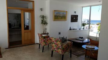 A dining area with a table and chairs, a potted plant, and a painting on the wall.