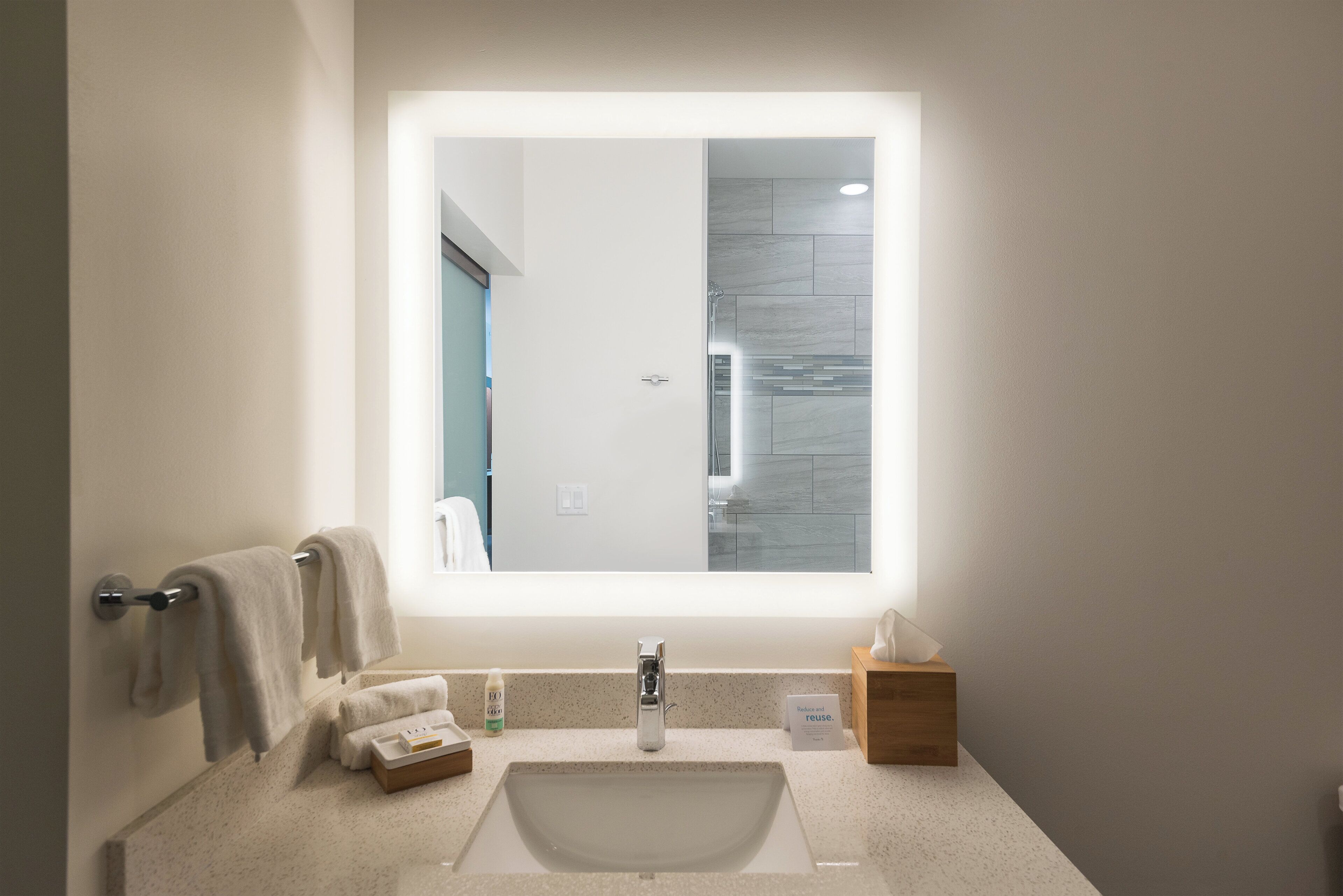 Un bagno con uno specchio grande, un lavandino e un porta asciugamani.