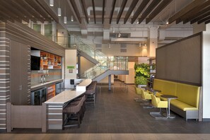 Eine moderne Bar mit einer langen Theke, mehreren Hockern und einer Treppe zu einer erhöhten Ebene.