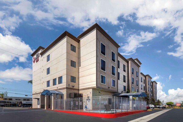 A multi-story hotel with a modern design, featuring a prominent entrance with a gated driveway and a covered outdoor seating area. - Best Western Plus Gardena Inn & Suites (Gardena)