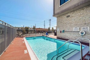 An outdoor swimming pool with a brick wall, a lifeguard chair, and a pool sign. - Best Western Plus Gardena Inn & Suites (Gardena)