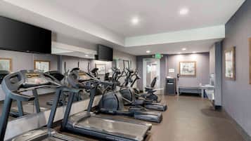 A gym with treadmills, elliptical machines, and a weight bench.