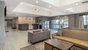 A modern lobby with seating areas, a reception desk, and a large window providing a view outside.