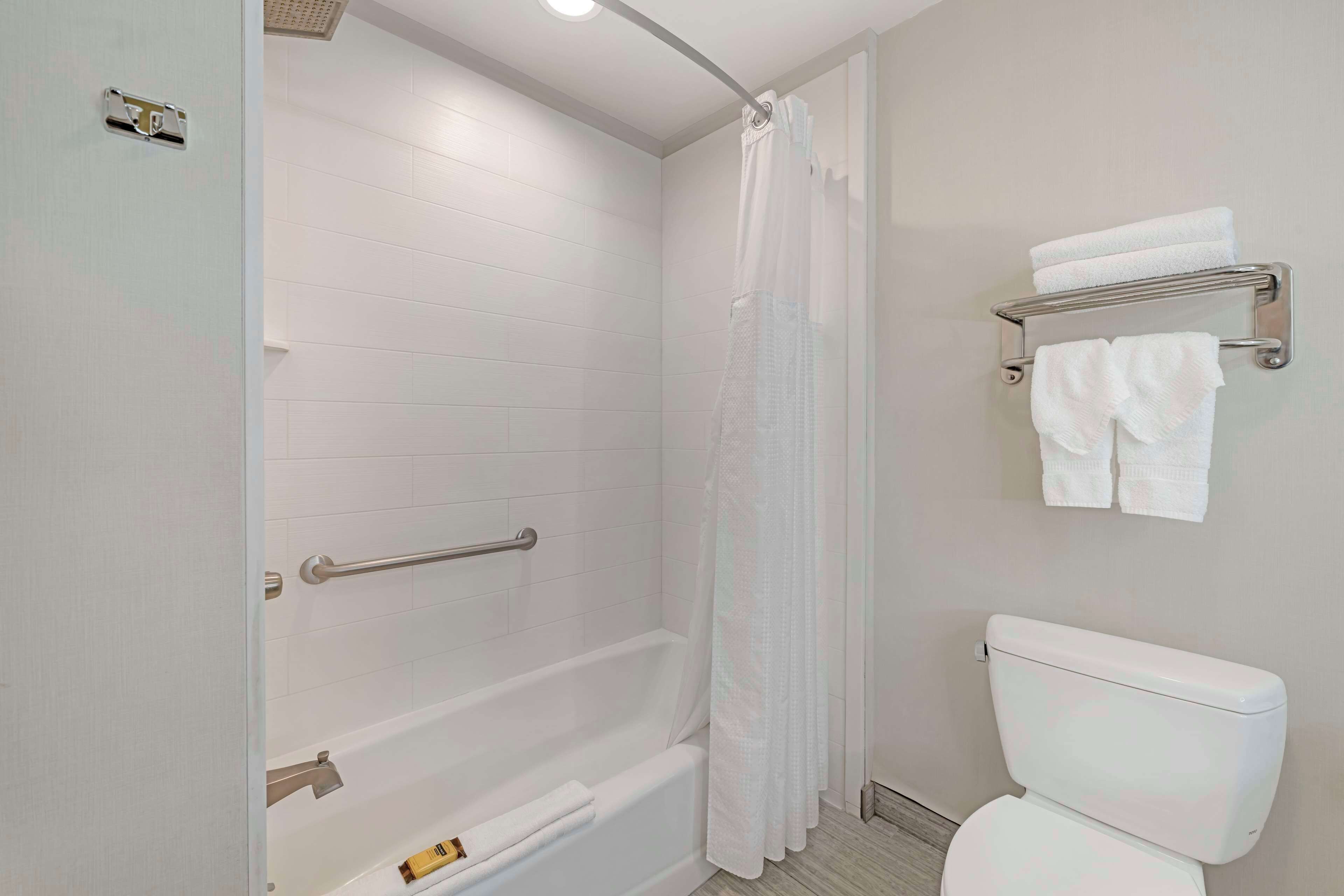 A bathroom with a bathtub, toilet, and towel rack.