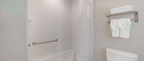 A bathroom with a bathtub, toilet, and towel rack.