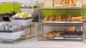 A breakfast buffet with various pastries, bread, and beverages.