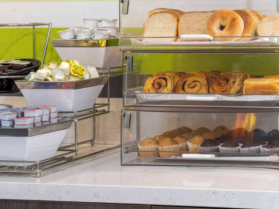 A breakfast buffet with various pastries, bread, and beverages.