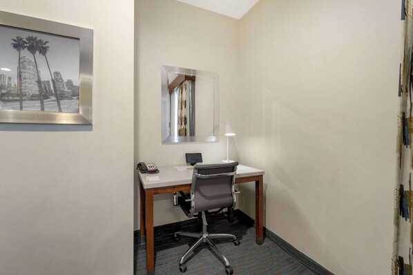 Una habitación de hotel con escritorio, silla y espejo.