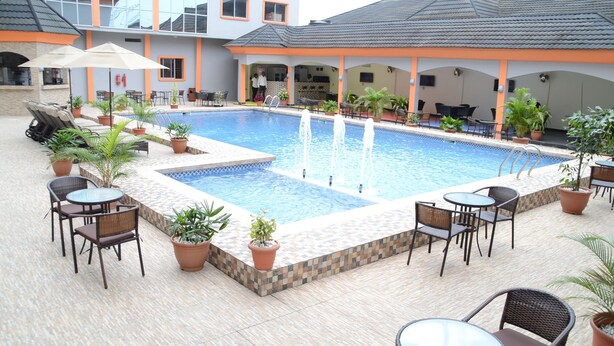 Piscina com deck revestido, rodeada por vasos de plantas e mobiliário de exterior.