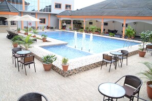 Une piscine dotée d’une terrasse carrelée, entourée de plantes en pot et de mobilier d’extérieur.