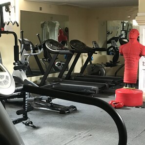 Une salle de sport équipée de matériel d’exercice, notamment des tapis de course et un vélo d’appartement.