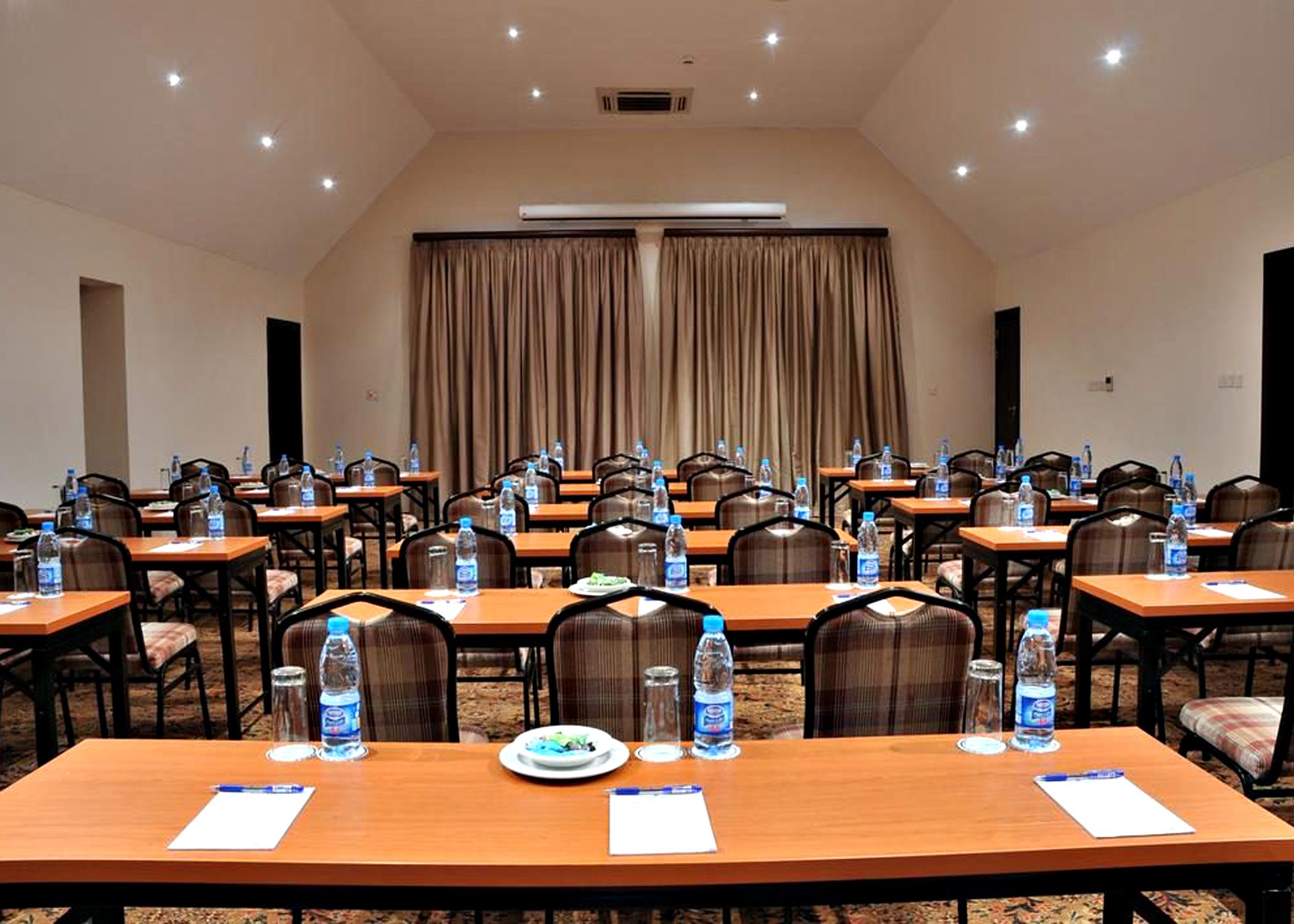A conference room with multiple tables, chairs, and water bottles.