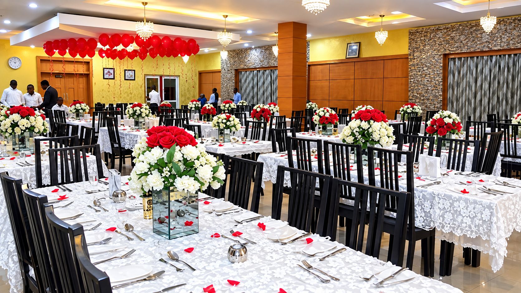 A banquet hall with multiple tables set for dining, each with a centerpiece of flowers.