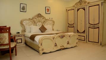 A bedroom with a large bed, a wooden chair, a nightstand, and a wardrobe.