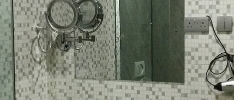 Un baño con lavamanos blanco, espejo y ducha.