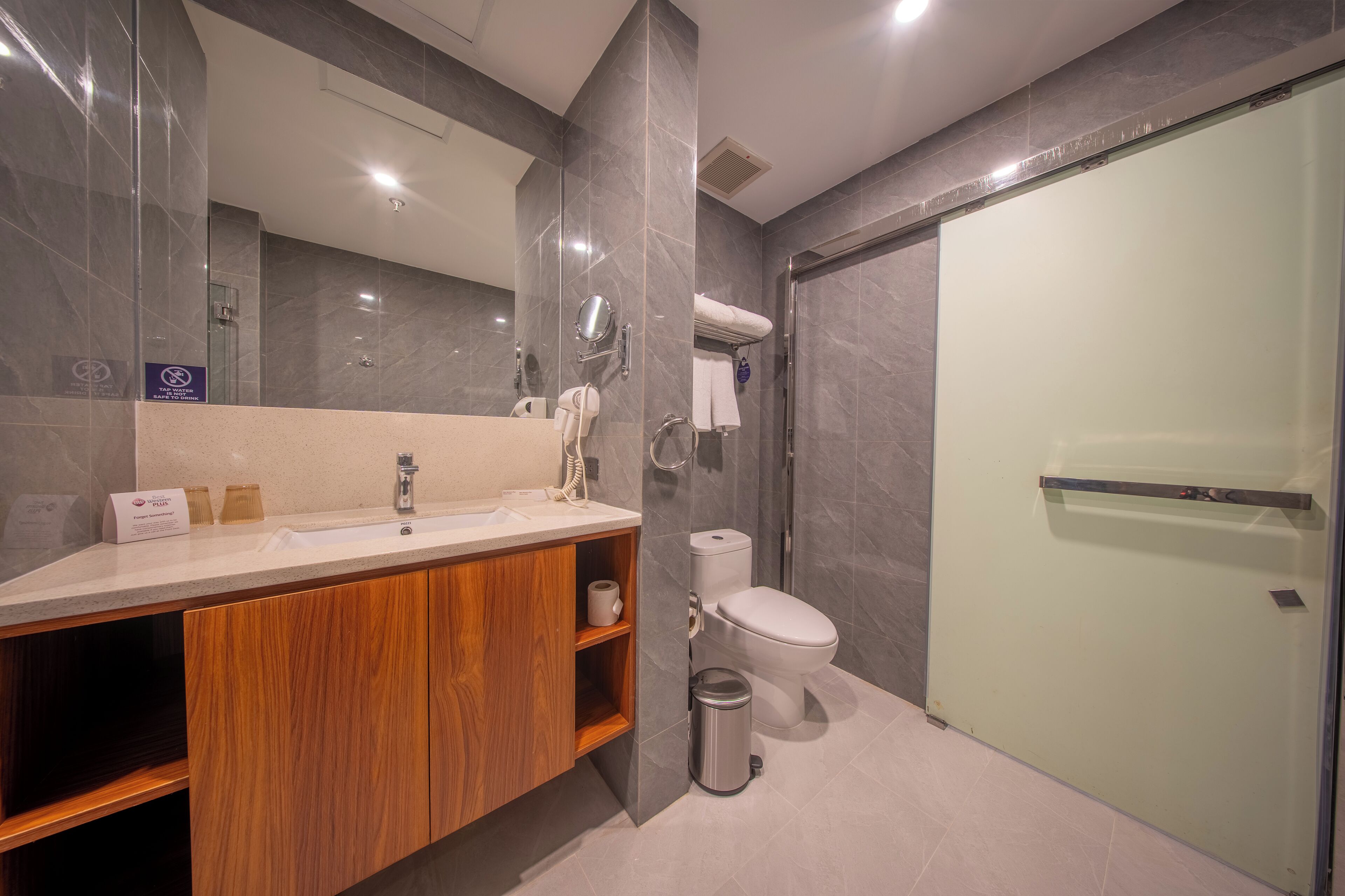 A modern bathroom with a wooden vanity, a glass shower enclosure, and a toilet.
