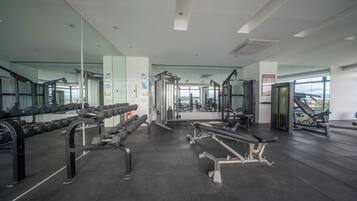 Ein modernes Fitnessstudio mit verschiedenen Trainingsgeräten, großen Spiegeln und Blick ins Freie.