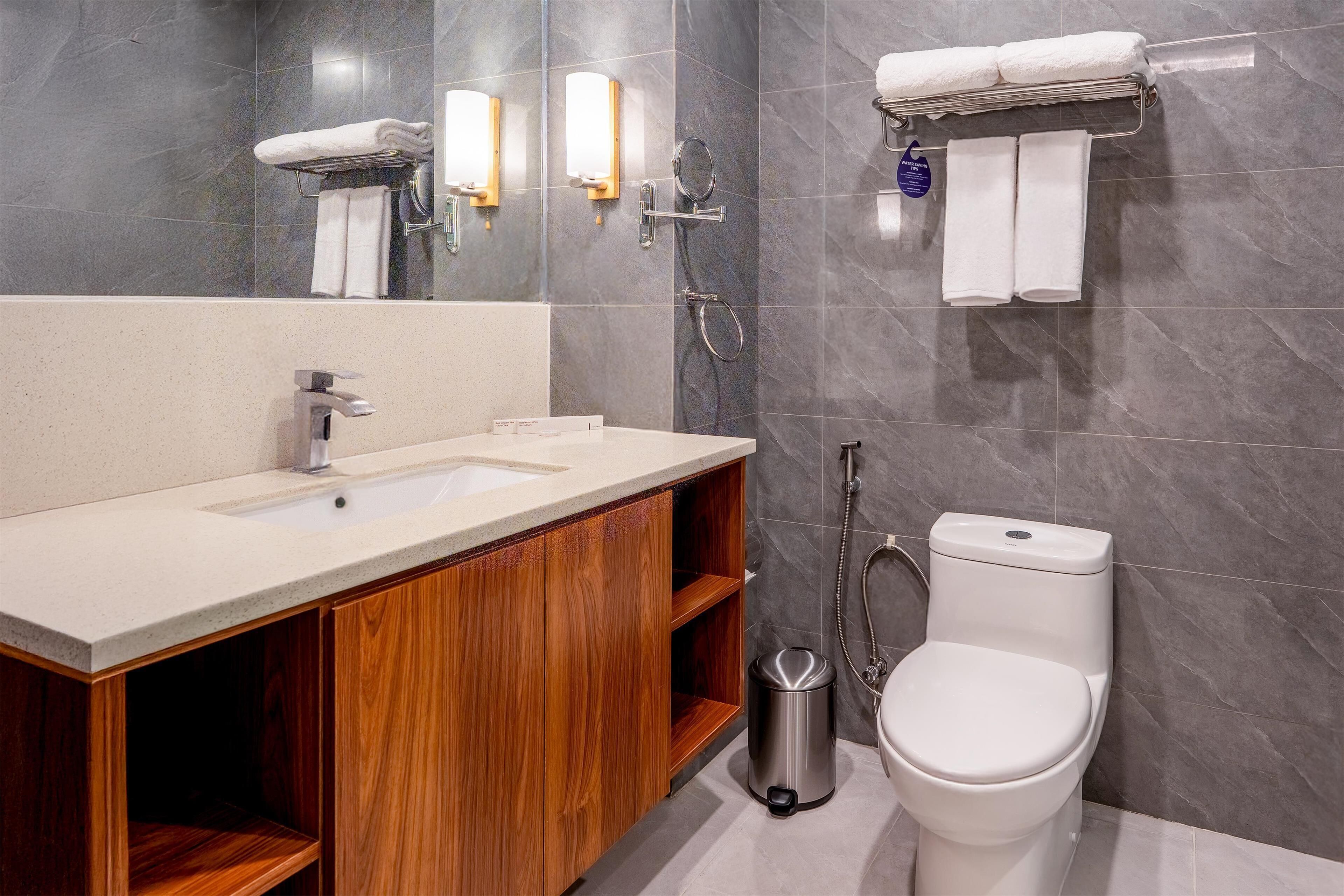 A modern bathroom with a wooden vanity, a sink, a toilet, and a towel rack.
