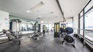 Une salle de sport moderne dotée de divers équipements d’exercice, de grandes fenêtres et d’un aménagement propre et spacieux.