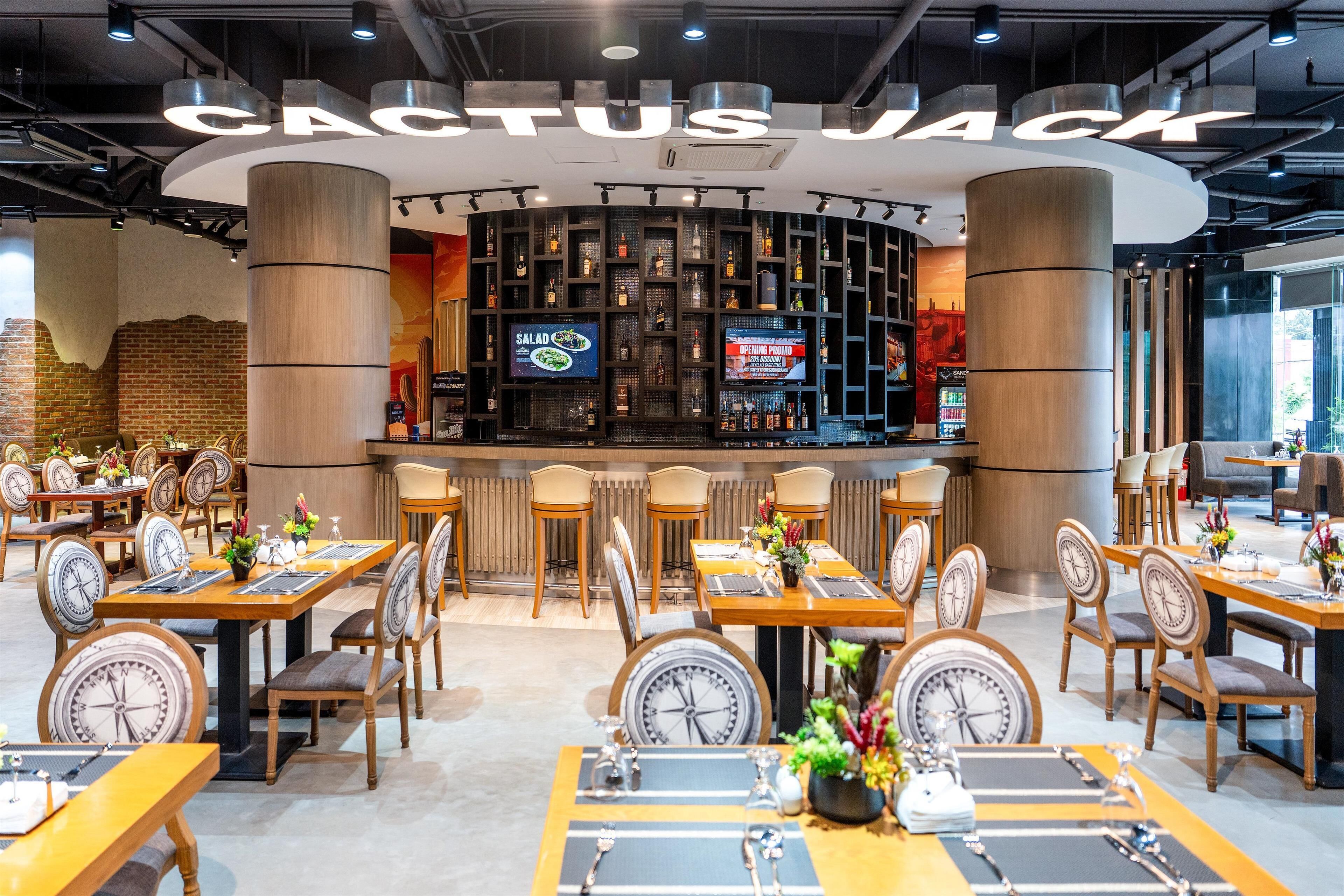 A restaurant with a modern interior, featuring a bar area with digital menu displays and a variety of seating arrangements.
