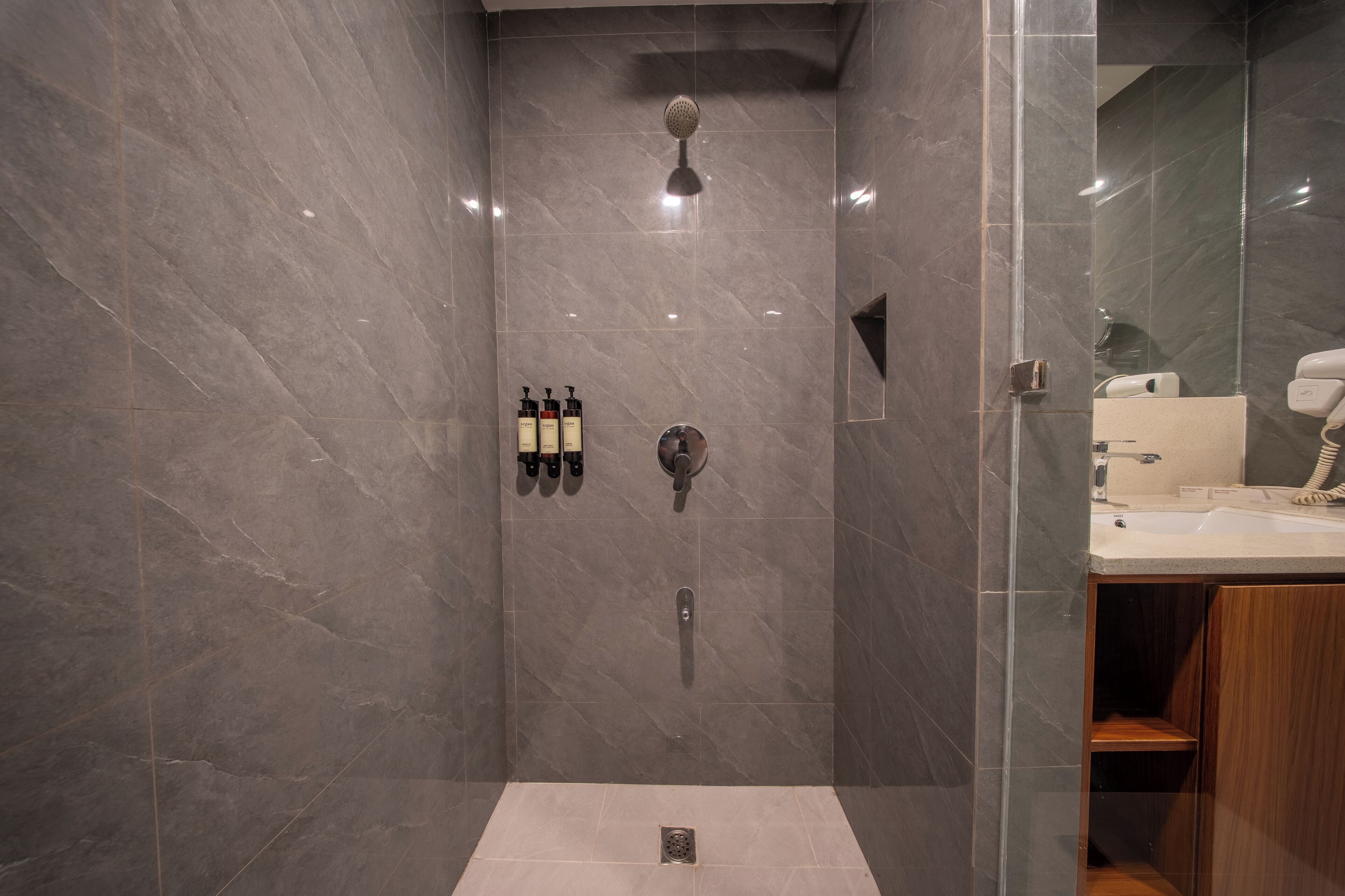 A modern bathroom with a shower, a sink, and toiletries on the wall.