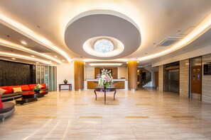 A spacious lobby with a reception desk, a staircase, and a seating area with sofas. - Best Western Plus Hotel Subic (Olongapo)