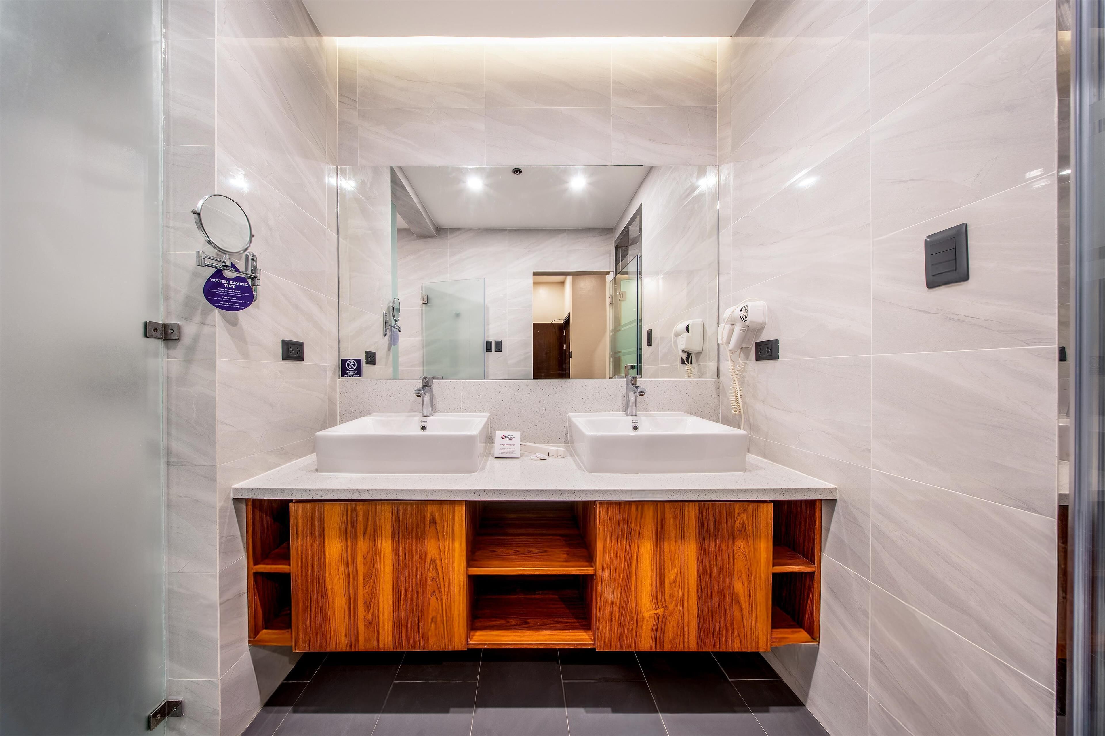 Un baño moderno con dos lavamanos, un espejo y un dispensador de toallas.