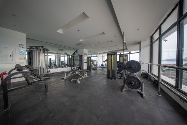 A gym with various exercise equipment, large windows, and a view of the outside. - Best Western Plus Hotel Subic (Olongapo)