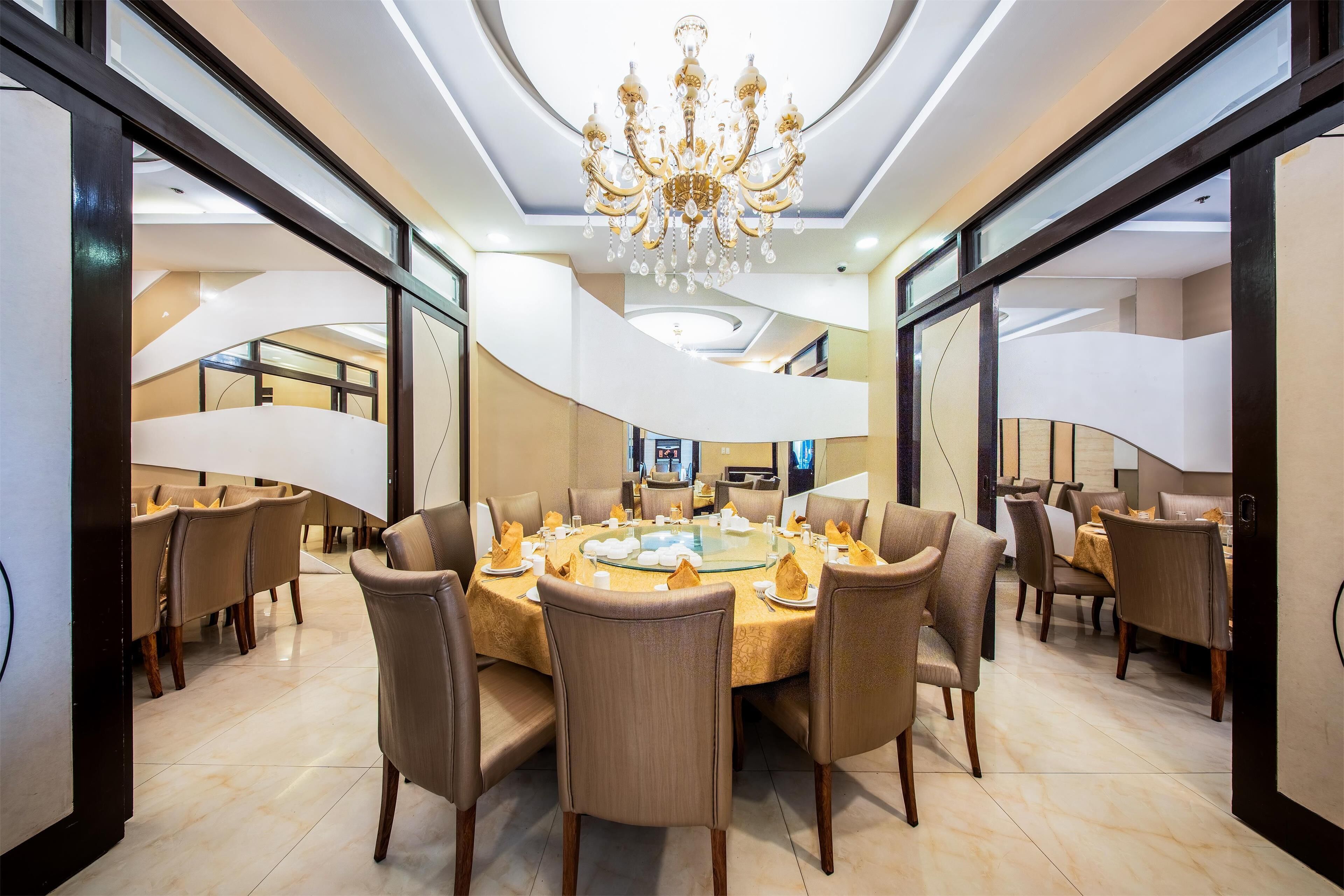 A modern dining area with a round table, multiple chairs, and a chandelier.